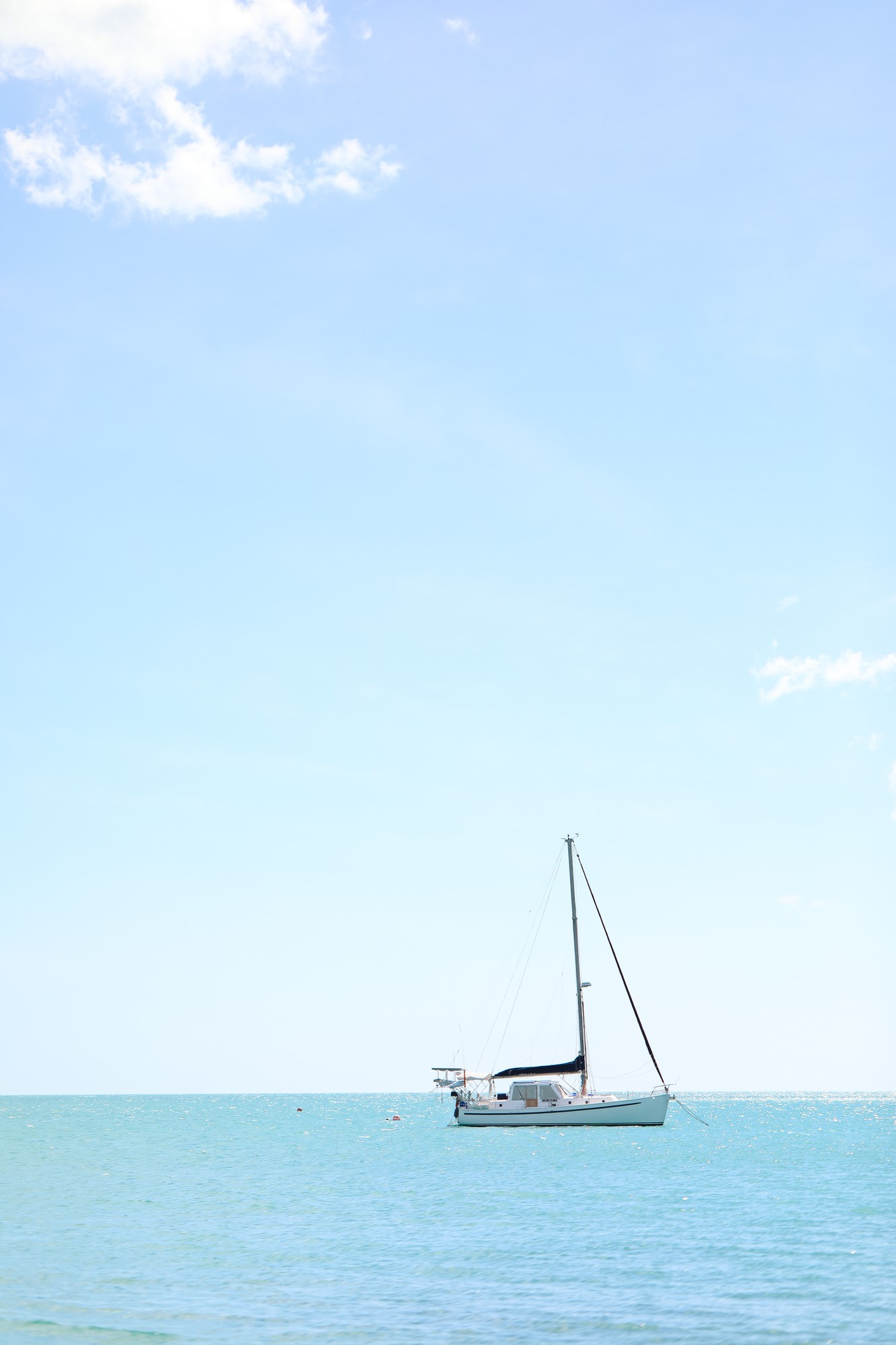 Aerial view of sailing boats moored along green pontoons in a quiet marina.（イメージ）